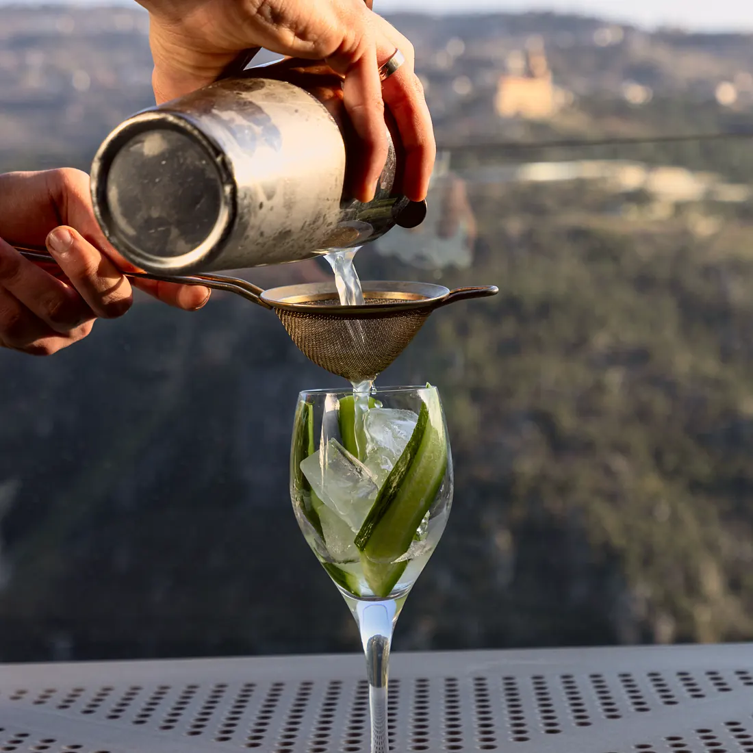 Bartender pouring a cocktail with the valley view at Scappa Bar